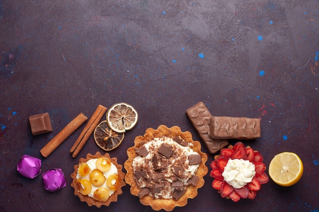 Vue de dessus de délicieux gâteaux avec de la cannelle et des bonbons sur la surface sombre