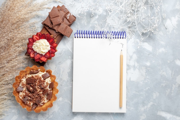 Vue de dessus de délicieux gâteaux crémeux avec des barres de chocolat sur le bureau blanc gâteau biscuit sweet bake