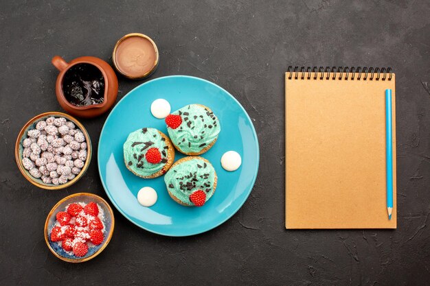 Vue de dessus de délicieux gâteaux crémeux avec des bonbons sur fond sombre dessert gâteau biscuit bonbons biscuits couleur