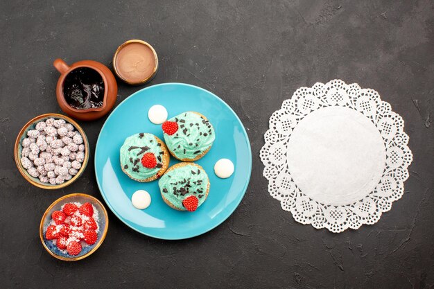 Vue de dessus de délicieux gâteaux crémeux avec des bonbons sur fond sombre dessert gâteau biscuit bonbons biscuits couleur