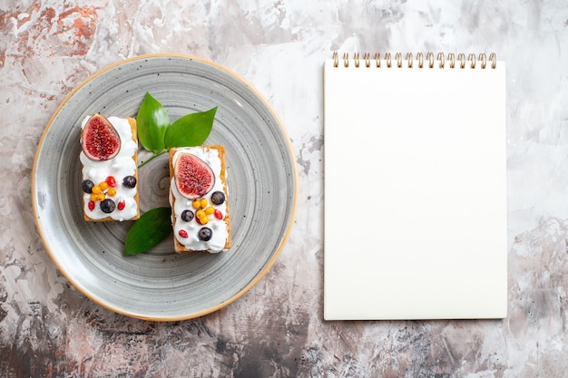 Vue de dessus de délicieux gâteaux crémeux avec des fruits frais sur fond clair