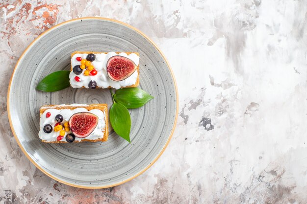 Vue de dessus de délicieux gâteaux crémeux avec des fruits frais sur fond clair