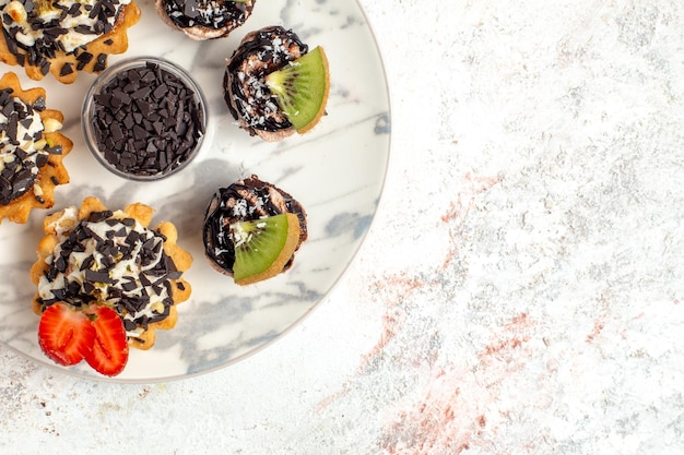 Vue De Dessus De Délicieux Gâteaux Crémeux Petits Desserts Pour Le Thé Avec Des Pépites De Chocolat Sur Une Surface Blanche Gâteau Aux Fruits Crème Biscuit Tarte Thé