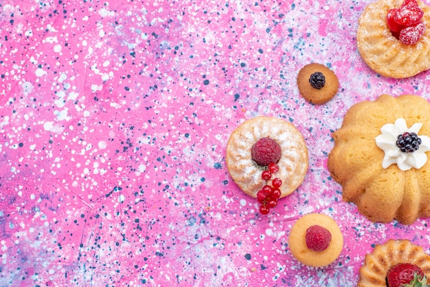 Photo gratuite vue de dessus de délicieux gâteaux cuits au four avec de la crème avec des baies sur un bureau violet vif, gâteau biscuit berry sweet bake