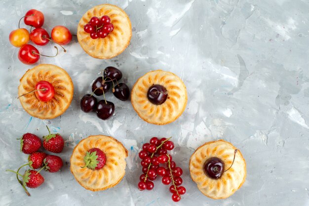 Une vue de dessus de délicieux gâteaux avec des fruits rouges moelleux et juteux sur le bureau léger gâteau aux fruits de baies gâteau au sucre