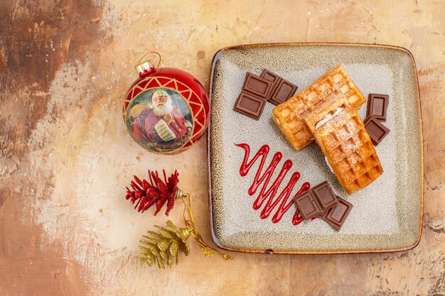 Vue de dessus de délicieux gâteaux gaufres avec des barres de chocolat sur le fond marron