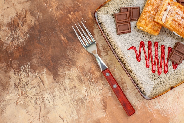 Vue de dessus de délicieux gâteaux gaufres avec des barres de chocolat sur le fond marron