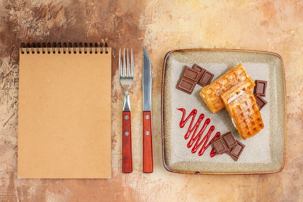 Vue de dessus de délicieux gâteaux gaufres avec des barres de chocolat sur le fond marron