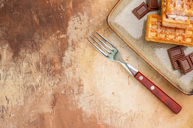 Vue de dessus de délicieux gâteaux gaufres avec des barres de chocolat sur le fond marron