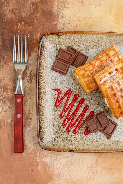 Vue de dessus de délicieux gâteaux gaufres avec des barres de chocolat sur le fond marron