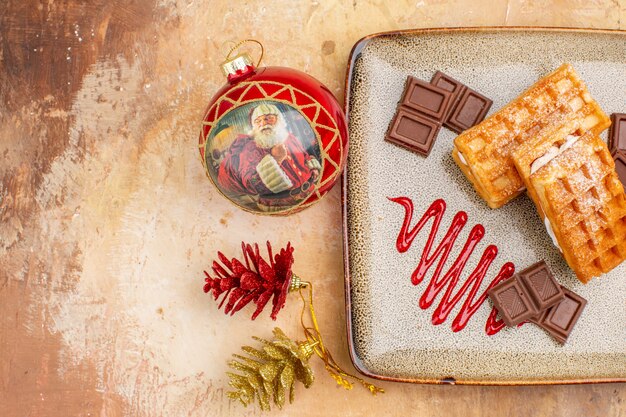 Vue de dessus de délicieux gâteaux gaufres avec des barres de chocolat sur le fond marron