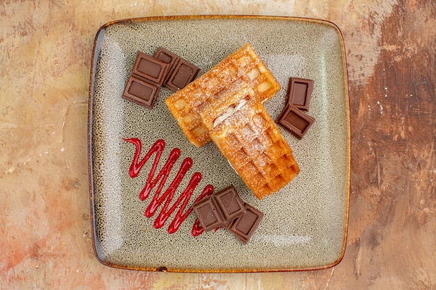 Vue de dessus de délicieux gâteaux gaufres avec des barres de chocolat sur le fond marron