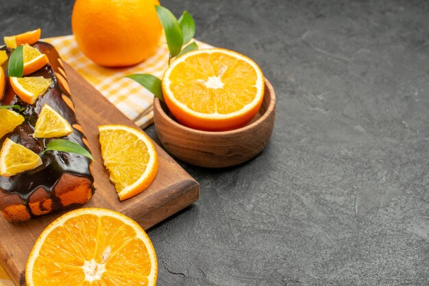 Vue de dessus de délicieux gâteaux mous entiers et citrons coupés avec des feuilles sur table sombre