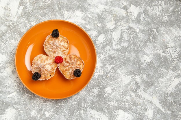 Vue de dessus de délicieux gâteaux de pâte avec du sucre en poudre à l'intérieur de la plaque sur un bureau blanc