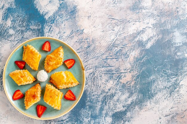 Vue de dessus de délicieux gâteaux sucrés aux fraises sur fond bleu