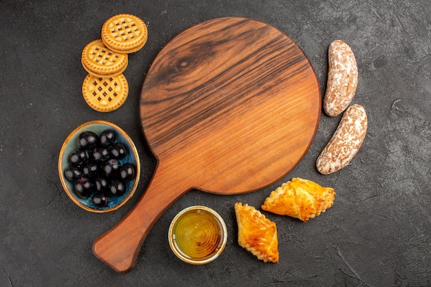 Vue de dessus de délicieux gâteaux sucrés aux olives et biscuits sur la tarte au gâteau sucré de surface sombre