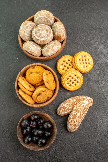 Vue de dessus de délicieux gâteaux sucrés avec des biscuits et des olives sur la surface sombre gâteau à tarte sucré