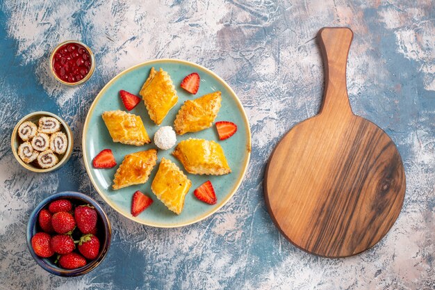 Vue de dessus de délicieux gâteaux sucrés avec des fruits sur fond bleu