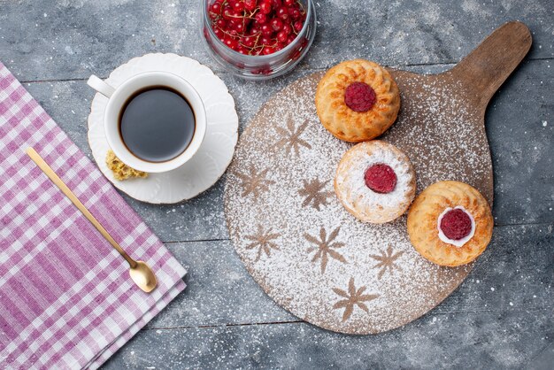 Vue de dessus de délicieux gâteaux avec une tasse de café et de canneberges rouges fraîches sur le bureau rustique gris biscuit fruit sucré