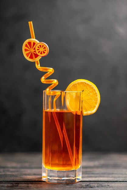 Vue de dessus de délicieux jus de fruits frais dans un verre avec citron vert orange et tube sur fond sombre