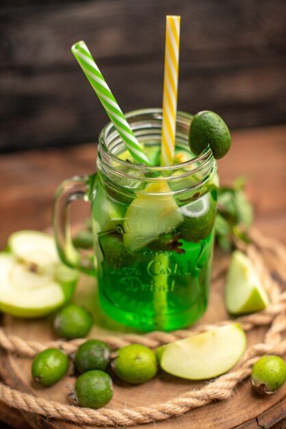 Vue de dessus de délicieux jus de fruits frais servis avec des pommes et des feijoas sur une planche à découper en bois