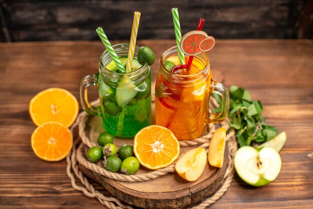 Vue de dessus de délicieux jus de fruits et fruits frais sur un plateau en bois sur fond marron