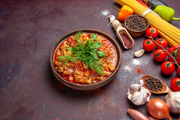 Vue de dessus de délicieux légumes cuits en tranches avec des légumes verts et des assaisonnements sur une sauce de bureau sombre