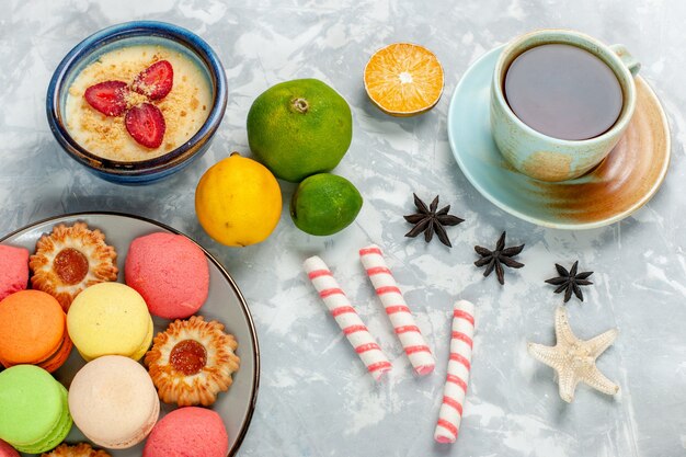 Vue de dessus de délicieux macarons français avec des biscuits dessert et thé sur un bureau blanc léger cuire au four gâteau biscuit sucre sweet photo