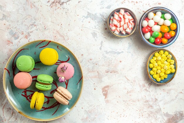 Vue de dessus de délicieux macarons français avec différents bonbons sur un biscuit biscuit blanc