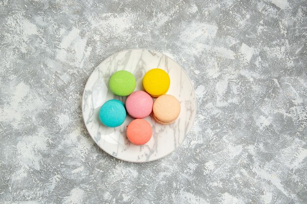 Vue de dessus de délicieux macarons français gâteaux colorés sur une surface blanche