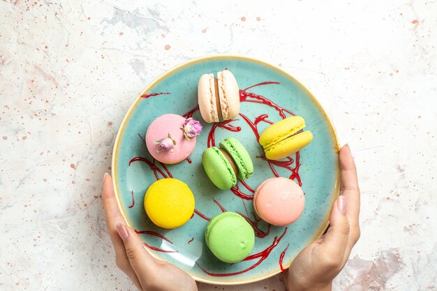 Vue de dessus de délicieux macarons français à l'intérieur de la plaque sur un gâteau blanc biscuit sucré