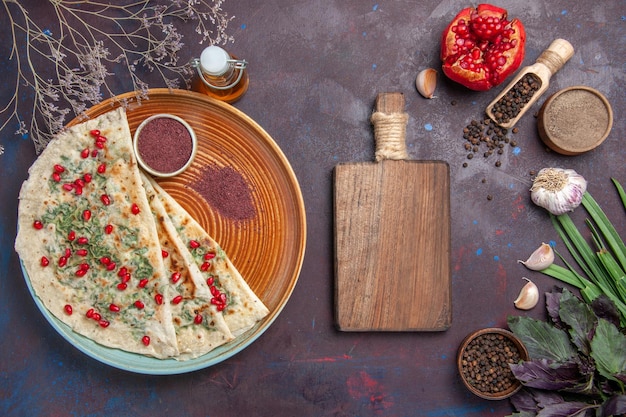 Vue de dessus de délicieux morceaux de pâte cuits qutabs avec des légumes verts sur la surface sombre plat de graisse de calories cuisson repas de pâte