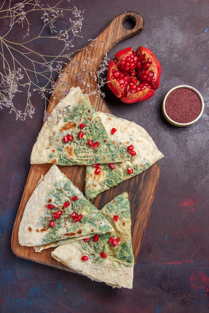 Photo gratuite vue de dessus de délicieux morceaux de pâte cuits qutabs avec des verts sur un bureau sombre calorie graisse plat de cuisson repas de pâte