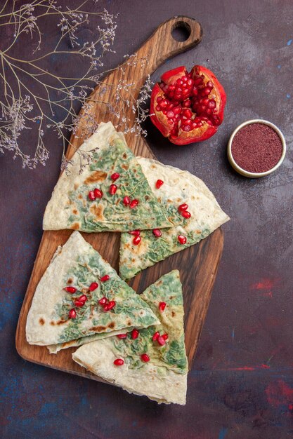 Vue de dessus de délicieux morceaux de pâte cuits qutabs avec des verts sur un bureau sombre calorie graisse plat de cuisson repas de pâte