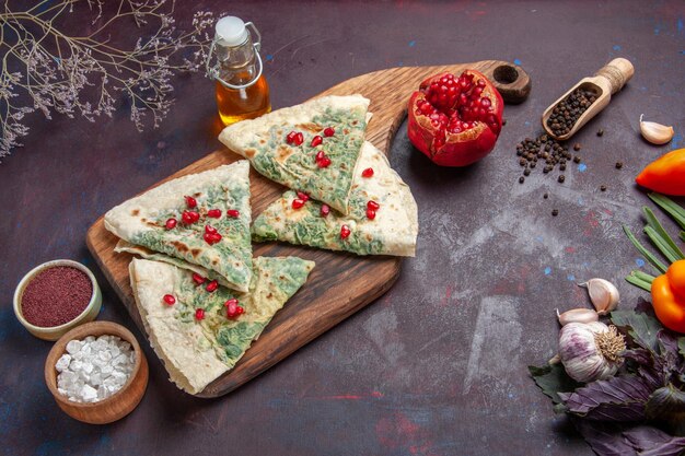 Vue de dessus de délicieux morceaux de pâte cuits qutabs avec des verts sur la surface sombre calorie graisse plat de cuisson repas de pâte