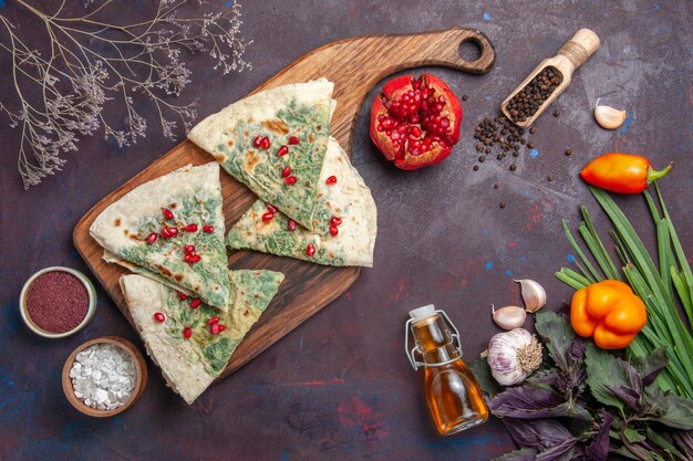 Vue de dessus de délicieux morceaux de pâte cuits qutabs avec des verts sur la surface sombre calorie graisse plat de cuisson repas de pâte