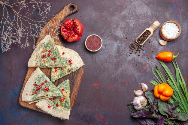 Vue de dessus de délicieux morceaux de pâte cuits qutabs avec des verts sur la surface sombre calorie graisse plat de cuisson repas de pâte