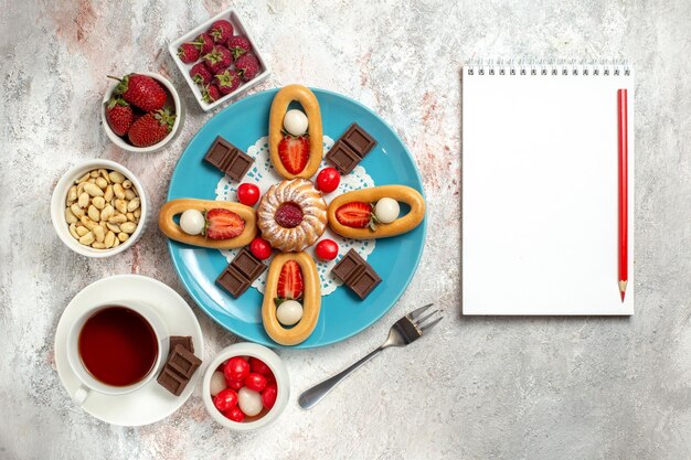 Vue de dessus délicieux petit gâteau avec des barres de chocolat thé et craquelins sucrés sur fond blanc biscuit sucré gâteau tarte au chocolat