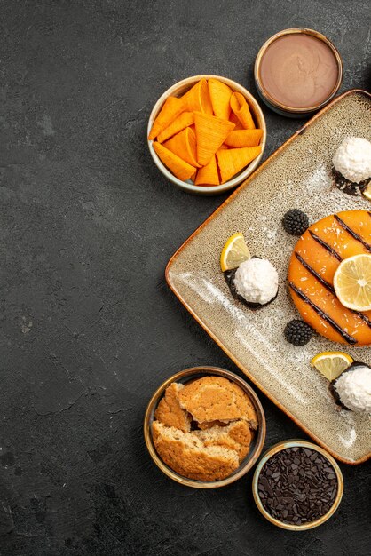 Vue de dessus délicieux petit gâteau avec des bonbons à la noix de coco sur un bureau gris foncé gâteau au thé biscuit biscuit dessert