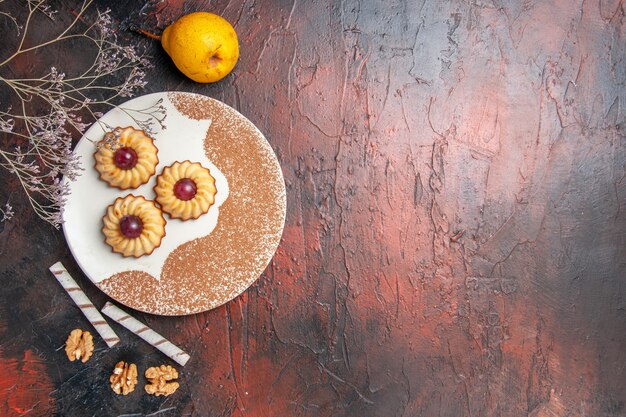 Vue de dessus délicieux petits biscuits à l'intérieur de la plaque sur la table sombre gâteau biscuits sucrés sucre