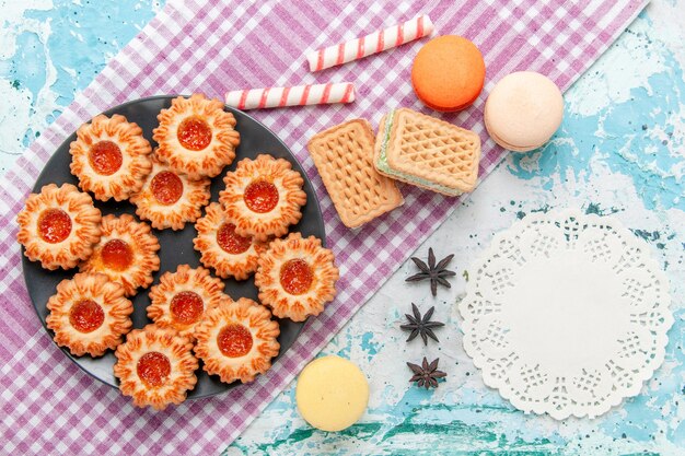 Vue de dessus de délicieux petits cookies avec des macarons à la confiture d'orange et des gaufres sur le bureau bleu biscuit biscuit thé sucré