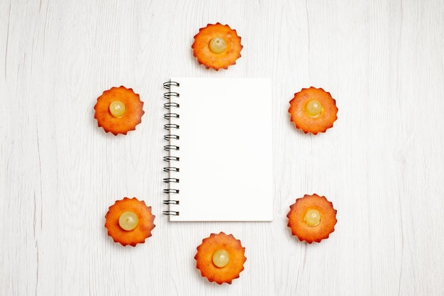 Photo gratuite vue de dessus de délicieux petits gâteaux bordés sur un bureau blanc dessert biscuit gâteau au thé tarte biscuit sucré