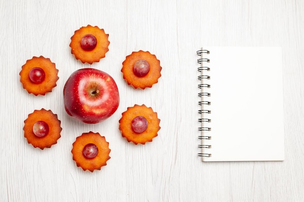 Photo gratuite vue de dessus de délicieux petits gâteaux avec des pommes fraîches sur une surface blanche dessert biscuit thé gâteau tarte biscuits