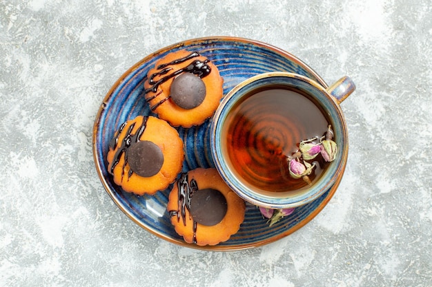 Vue de dessus de délicieux petits gâteaux avec une tasse de thé sur une surface blanche gâteau biscuit biscuit dessert thé sucré