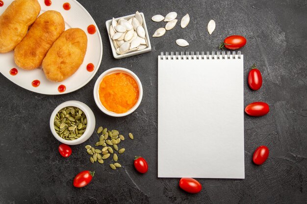 Photo gratuite vue de dessus de délicieux petits pains aux pommes de terre avec de petites tomates sur fond sombre