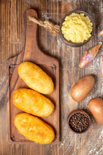 Vue de dessus de délicieux petits pains aux pommes de terre avec de la purée de pommes de terre sur un bureau en bois cuire au four la couleur de la pâte au poivre