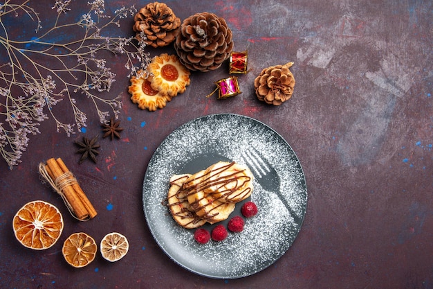 Vue de dessus de délicieux petits pains sucrés à l'intérieur de la plaque sur fond sombre rouleaux de pâte à biscuit gâteau sucré