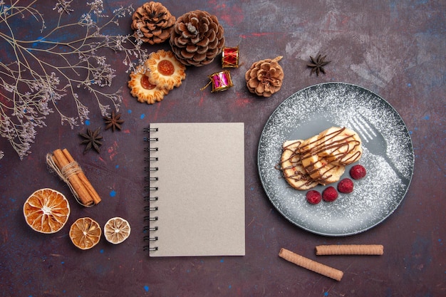 Vue de dessus de délicieux petits pains sucrés tranchés de bonbons pour le thé à l'intérieur de la plaque sur fond sombre rouleaux de pâte à biscuits gâteau sucré