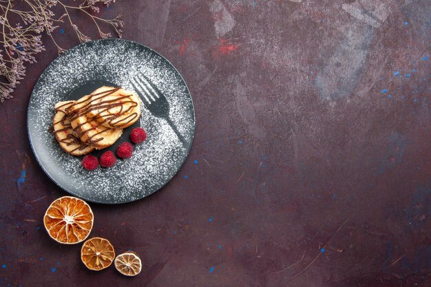 Vue de dessus de délicieux petits pains sucrés en tranches de gâteau pour une tasse de thé sur fond sombre rouleaux biscuit tarte sucrée gâteau au thé dessert