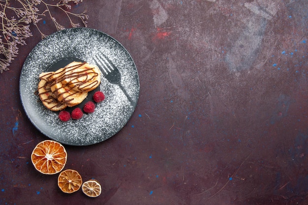 Vue de dessus de délicieux petits pains sucrés en tranches de gâteau pour une tasse de thé sur fond sombre rouleaux biscuit tarte sucrée gâteau au thé dessert